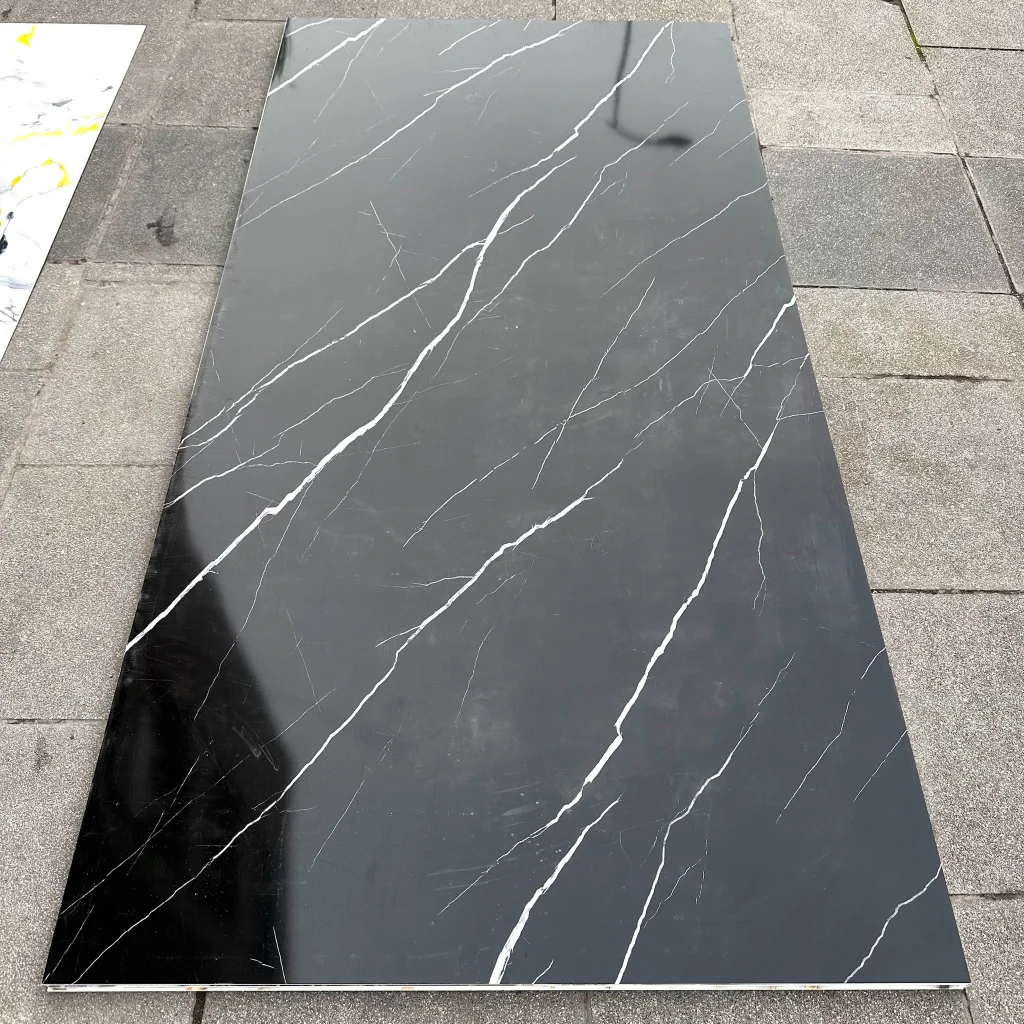 PVC Mermer Panel Night modeli, koyu siyah ve antrasit tonları üzerine ince beyaz damar detaylarıyla tasarlanmış dekoratif PVC duvar panelidir. Modern, minimalist ve premium iç mekân dekorasyonlarında TV ünitesi arkası, salon, showroom, otel, restoran, ofis, banyo ve mutfak duvar kaplamalarında kullanılan estetik mermer görünümlü PVC panel çözümüdür. Parlak yüzeyli, su geçirmez ve kolay temizlenebilir PVC-polimer yapısıyla uzun ömürlü kullanım sağlar. Night mermer deseni, gece taşını andıran koyu yüzeyi ve zarif damar yapısıyla mekânlara sofistike, modern ve güçlü bir atmosfer kazandırır.